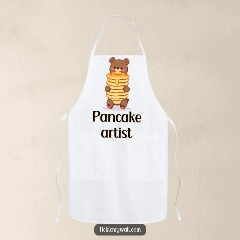 Funny apron featuring a clumsy bear comically attempting to balance a wobbly stack of three pancakes. Great for kitchen humor.