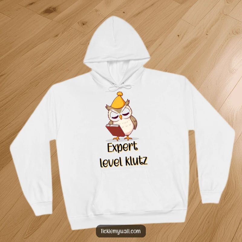 Funny hoodie showing a clumsy owl in a hat fumbling a book, designed for comfort and comedic relief.